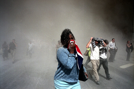 Gilles Peress- Magnum Photos. 
Una donna tenta di coprirsi il volto per non respirare la polvere e il fumo