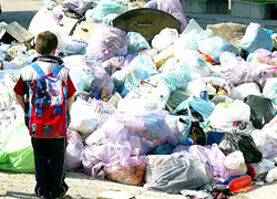 Un bambino davanti ad una montagna di pattumiera