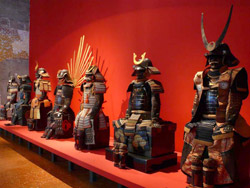 Samurai Le armature in mostra che risaltano sul pannello rosso nell'allestimento di Daniela Ferretti